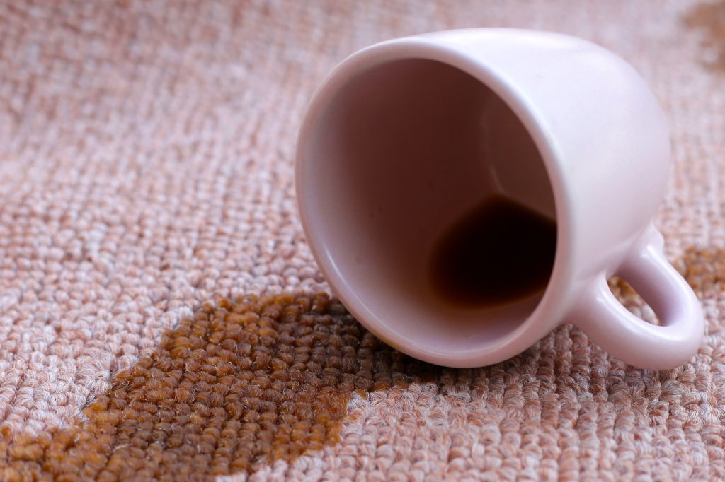 Coffee spilled from white cup on the carpet